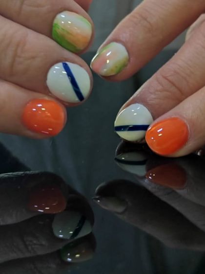 An abstract and colorful design on short nails, featuring orange, white, and watercolor-like patches.