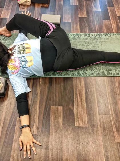 A student holds a deep twisting pose, demonstrating the strength and flexibility gained through our training.