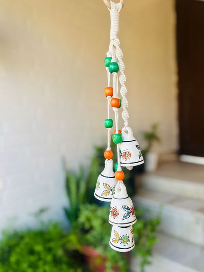 A close-up of our 'Symphony Chimes' in the 'Marigold' variant. The intricate macrame knots, colorful wooden beads, and hand-painted ceramic bells make these a perfect gift for any occasion.