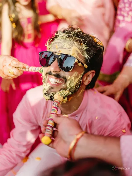 The groom smiling through a face full of haldi, a classic and fun shot from the Haldi ceremony.