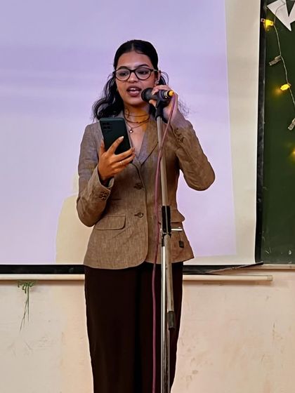 A confident student poet on stage at Gargi College. We provide a platform for young voices to be heard and celebrated.