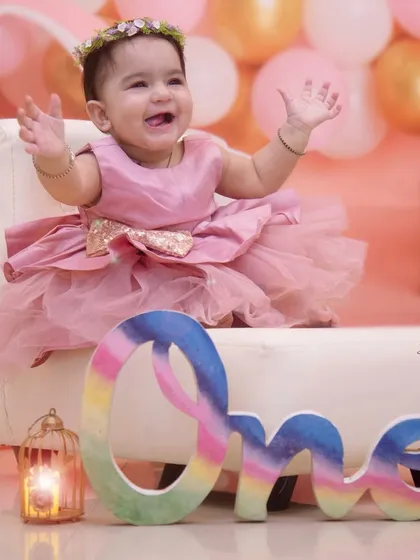 Who needs a crown with a smile this cute? This little princess is overjoyed during her first birthday session, complete with a colorful 'One' sign.