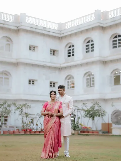 A stunning wide shot in a beautiful location. The bride's pink saree and the groom's pastel sherwani are a perfect match.