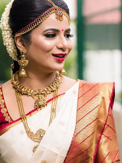 The epitome of South Indian bridal elegance. For this look, I paired a classic red lip and winged eyeliner with traditional gold temple jewellery and a fragrant jasmine hair arrangement, complementing her beautiful white and red silk saree.