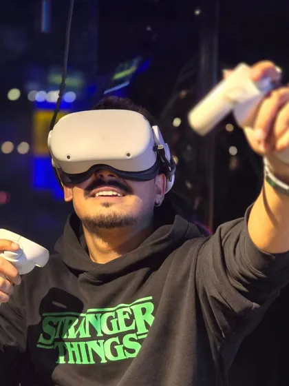 A player wearing a Stranger Things hoodie is lost in a VR world, controllers ready for action.