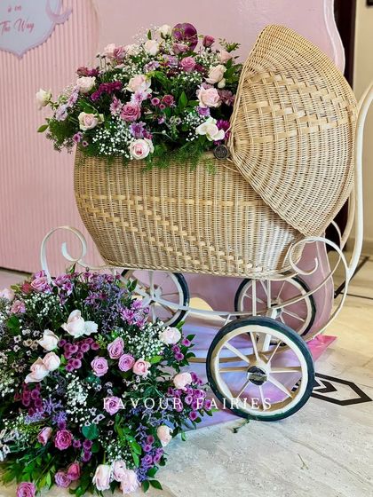 A close-up of the vintage-style baby carriage prop, overflowing with beautiful pink and purple flowers. This piece adds a touch of whimsy and elegance to any baby shower.
