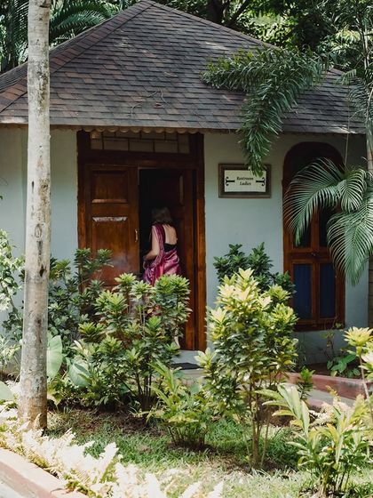 A guest enters one of our heritage rooms, giving a glimpse of the traditional architecture and surrounding greenery.