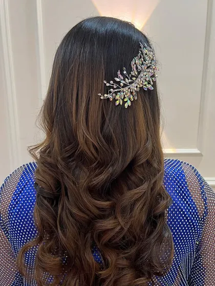 A glamorous hairstyle for a reception or cocktail party, featuring soft waves and a sparkling crystal hairpiece.