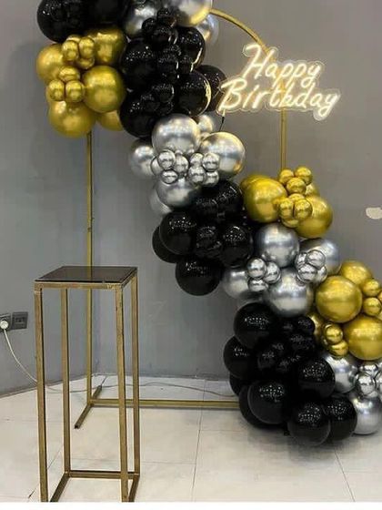 A minimalist and modern half-arch on a gold stand, using black, gold, and silver chrome balloons.