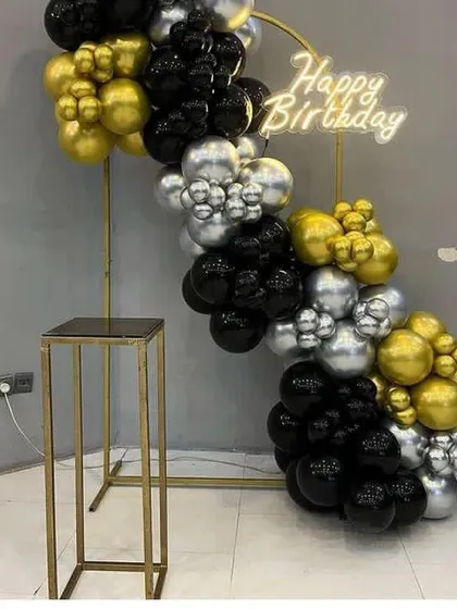 A minimalist and modern half-arch on a gold stand, using black, gold, and silver chrome balloons.