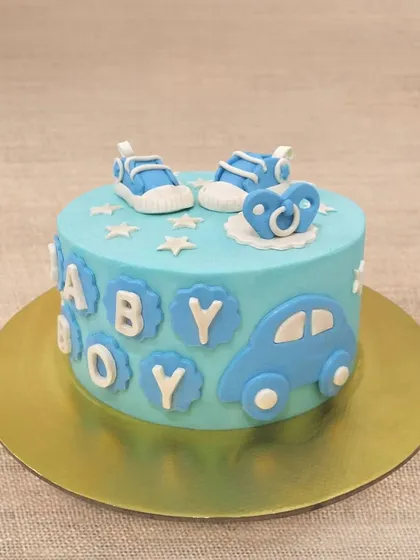 A sweet "Baby Boy" cake in shades of blue, decorated with a car, pacifier, and tiny sneakers.