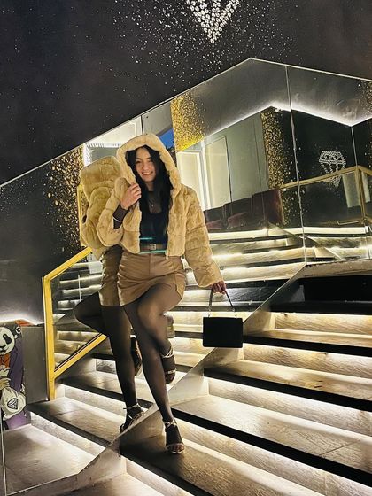 A fun, cozy look with the hood of the fur jacket up, adding a playful touch to the stylish outfit.