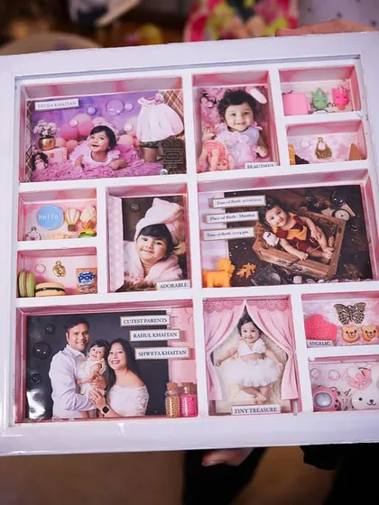 A full view of the baby girl's story frame, held by her parents, showcasing the intricate details in every compartment.