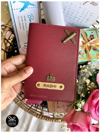 A personalized passport holder with the recipient's name and custom charms. This is a great standalone gift or a perfect addition to a travel-themed hamper.