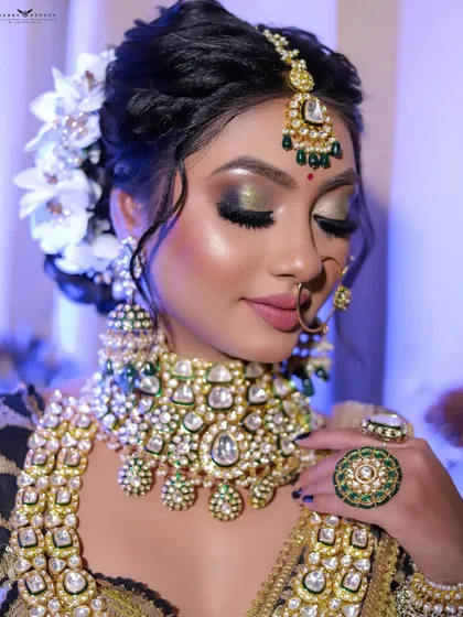 A close-up with the bride's eyes closed, highlighting the shimmering green and gold eye makeup.