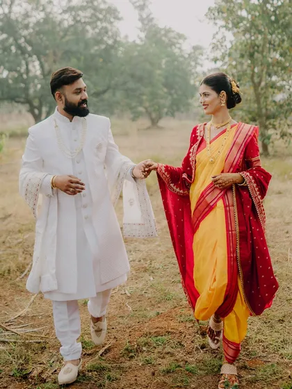 A candid shot of the couple walking hand-in-hand through a field. The movement and their happy interaction create a dynamic and natural portrait.