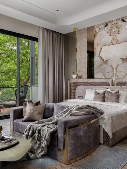 We believe a master bedroom should be a personal sanctuary. Here, we created a restful escape by combining warm, muted tones with rich textures. The statement book-matched marble panel behind the bed serves as a stunning focal point, complemented by a custom upholstered headboard, a curved velvet sofa, and large sliding doors that connect the room to the serene balcony view.