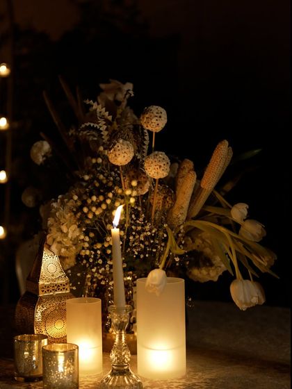 An ethereal centerpiece from the all-white Sufi night, featuring dried elements, baby's breath, and white tulips, all illuminated by the soft glow of candles.