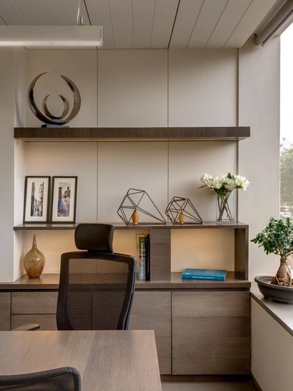 This executive cabin was designed with well-being in mind. A large window infuses the space with daylight, while the clean lines of the furniture and shelving create an organized and calming environment.