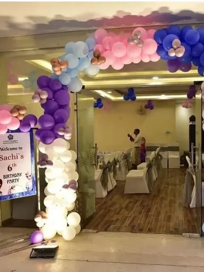 A welcoming entrance for a 6th birthday party, featuring a large balloon arch in pastel colors.