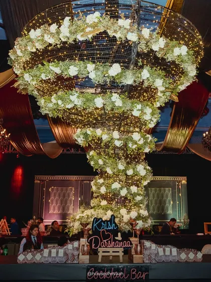 A massive floral tornado installation, lit with fairy lights, serves as a spectacular bar centerpiece, showcasing our ability to create large-scale, jaw-dropping structures.