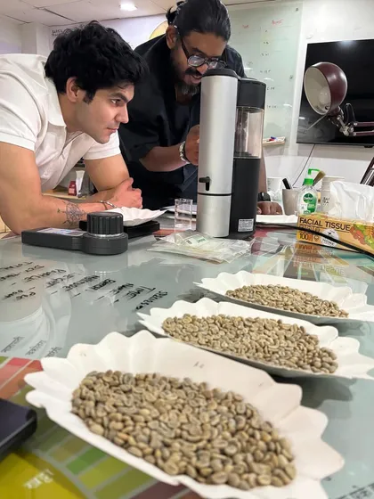A trainer showing a student how to use a sample roaster. This hands-on experience is crucial for understanding how roasting impacts flavor.