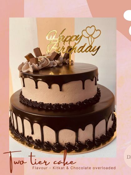 Another view of a two-tier chocolate drip cake, this one featuring KitKat bars and a 'Happy Birthday' topper. It combines popular candies with classic cake design.
