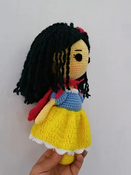 A side view of my handmade Snow White doll, showing the details of her classic dress with its blue bodice, yellow skirt, and red cape.