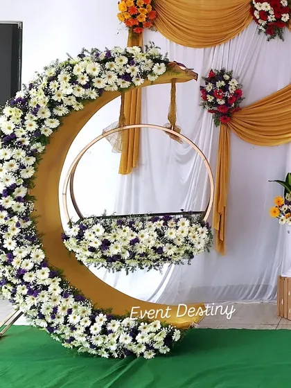 A close-up of my popular crescent-moon cradle design. I cover the entire structure with fresh white daisies and other flowers, making it a stunning centerpiece for any naming ceremony or baby shower.