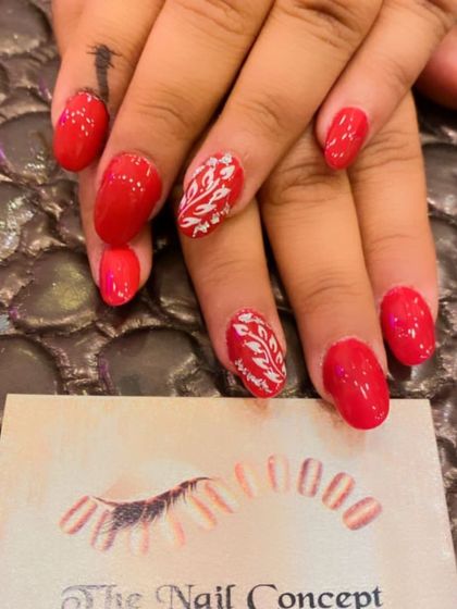 A simple and elegant set of bright red almond nails. The ring fingers are accented with a delicate, hand-painted white leaf pattern.
