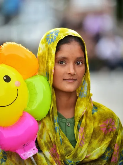 A portrait of a balloon seller on the streets. Her direct gaze and the colorful balloons create a striking contrast, telling a story of daily life and work.