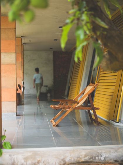 A simple wooden deck chair sits on the veranda, inviting a moment of pause. The design of 'Aamra' is filled with these "points of rest," blurring the boundary between inside and outside and encouraging a slower pace of life.