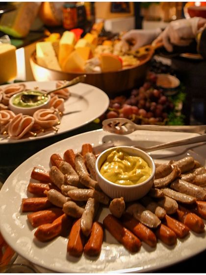 A platter of sausages and cold cuts with mustard, part of our charcuterie selection, perfect for a sophisticated cocktail hour.