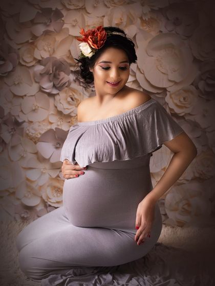 A beautiful solo shot against a floral background. The way she is looking down at her bump is a classic expression of a mother's love.