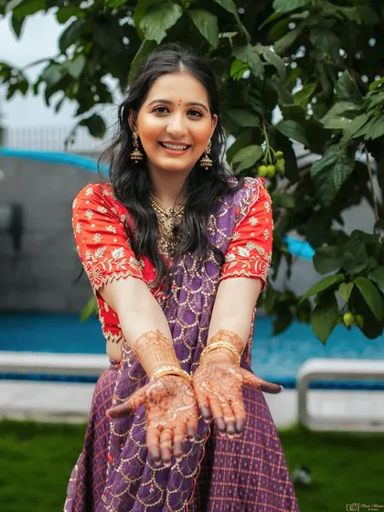 A joyful shot of the bride showing her henna. Her fresh-faced Roka makeup, with its soft and smooth base, makes her look absolutely radiant and happy.