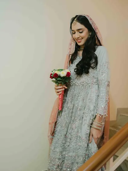 The bride descending the stairs with her bouquet, a classic and beautiful shot capturing her anticipation and the flow of her intricate gown.