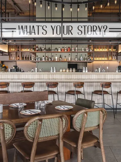 For Prequel, the bar is the heart of the space. We placed the brand's tagline, 'What's your story?', front and center to spark conversation, creating a focal point that is both a service area and a statement piece reflecting the restaurant's social, narrative driven identity.