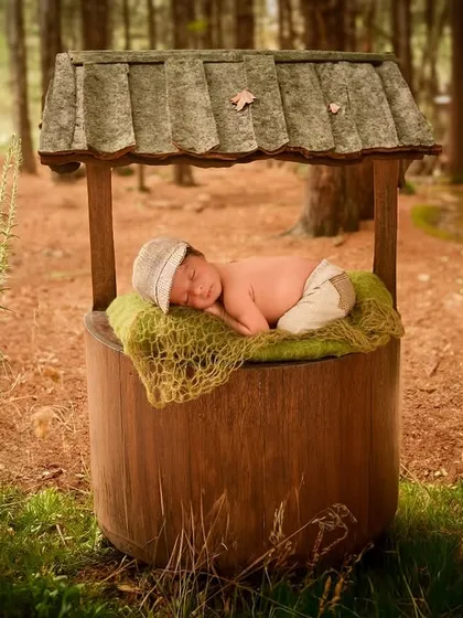 Using digital artistry, we placed this sleeping newborn safely on a mossy bed atop a wishing well in a magical forest setting.