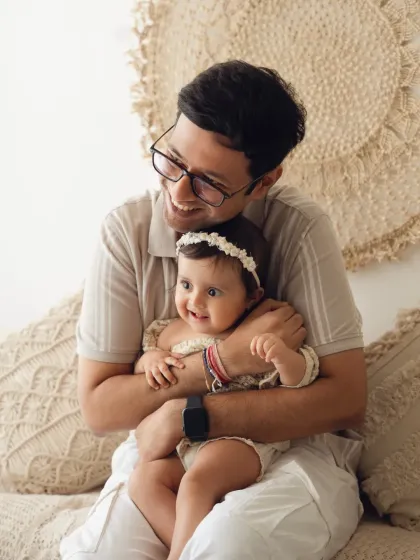 A father laughs as he cuddles his baby girl in a boho-chic studio setting. This portrait radiates warmth and paternal love.