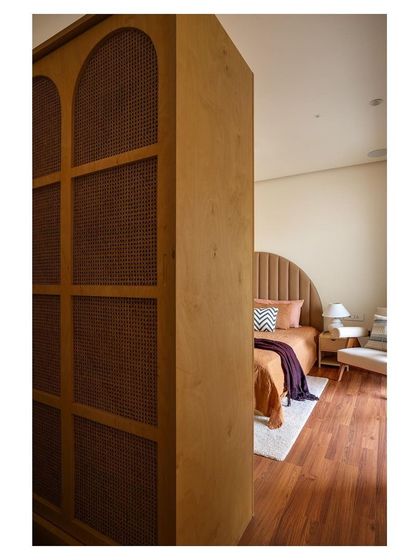 A detail shot showing the custom arched wardrobe with cane paneling we designed for this bedroom. This piece complements the matching headboard and adds a layer of traditional texture and warmth to the room.