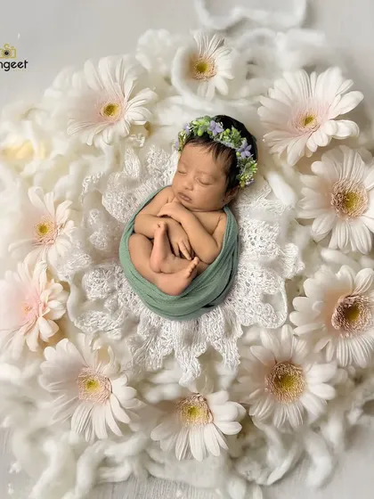 A delicate flower in a bed of daisies. This overhead shot of a newborn nestled in soft white petals highlights their tiny features and peaceful sleep, creating a pure and angelic portrait.