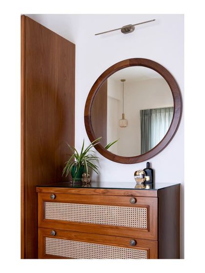 A detail of the rattan chest of drawers and circular mirror in the master bedroom. These pieces enhance the room's sense of spaciousness and brightness while adding to its aesthetic appeal.