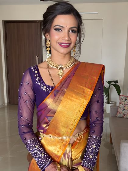 This bride is the picture of modern tradition, wearing a vibrant Kanjivaram saree with a contemporary blouse. Her makeup features a radiant finish and a bold lip to match her confident smile.