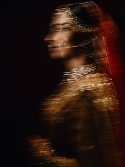 An abstract, motion-blur portrait of the bride, creating an artistic impression of her golden attire and the movement of the celebration.