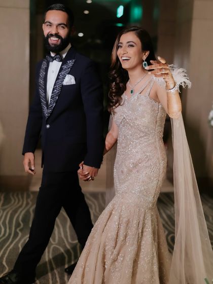 A candid moment of pure joy. This couple is walking into their cocktail party, and the bride's retro glam makeup and hair look effortlessly chic and full of life.
