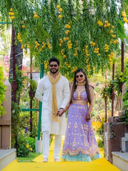 A lovely couple portrait during their Mehendi function. The backdrop of hanging marigolds and lush greenery creates a beautiful and natural setting for their photos.