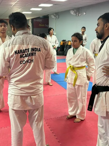 A coach providing instruction to a young yellow-belt student during the belt grading. Personal attention is key to proper development.