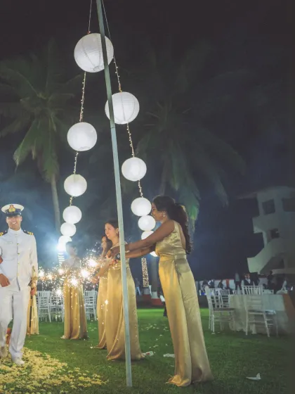 The couple makes their way into the reception, guided by bridesmaids holding sparklers. This shot captures the magic and excitement of the evening celebration.