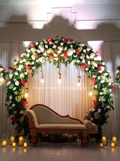 An elegant floral ring stage for a Christian wedding or reception. The full arch of red and white flowers is accented with hanging bulbs and candles.