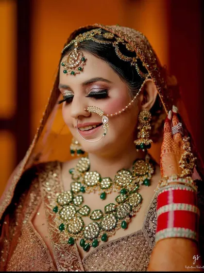 A beautiful and alluring bride wearing a heavy, floral-motif kundan set with green beads.